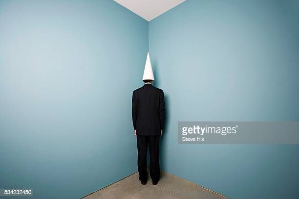businessman-wearing-dunce-cap-standing-in-corner-picture-id534232450.jpg
